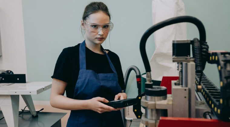 Koruyucu ekipmanlı bir operatör, fabrika ortamında CNC tezgâhının kontrol panelini kullanarak üretim yapıyor.